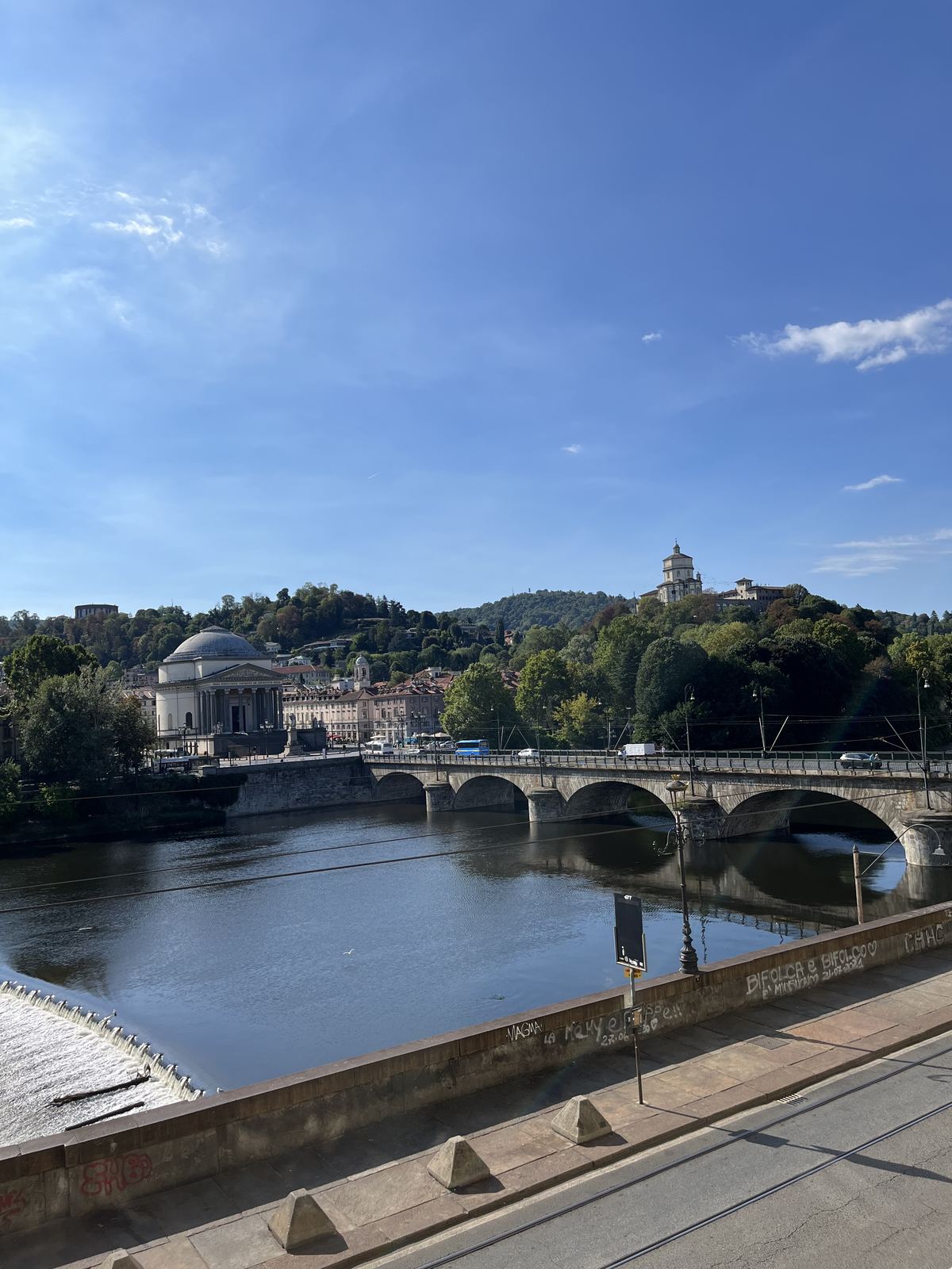 The river Po, a stone bridge and the Gran Madre church in Torino under a blue sky