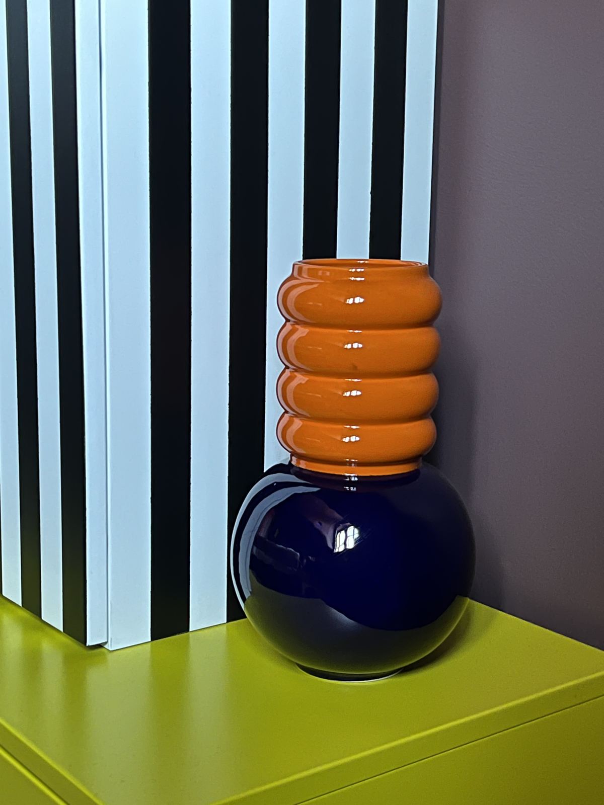 Stacked orange and blue ceramic lamp base on a lime-green plinth