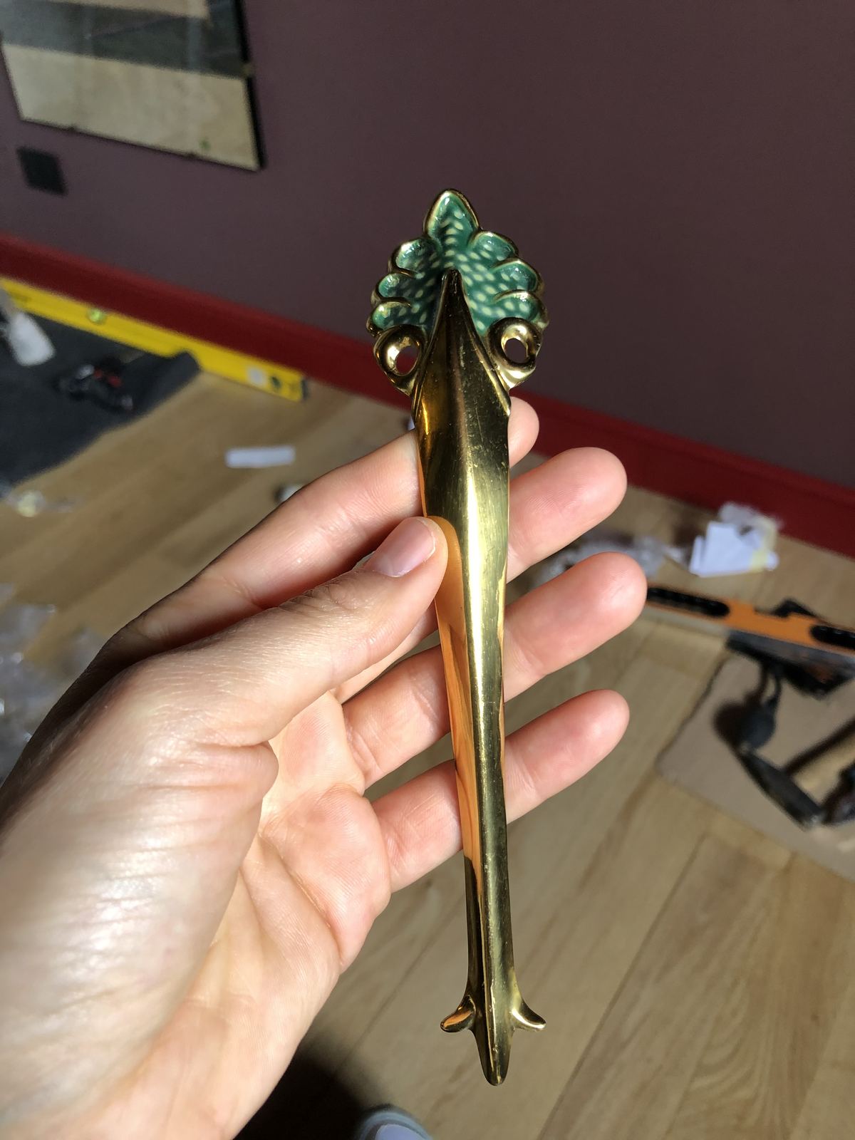 Brass handle with a green enamel leaf held in a hand