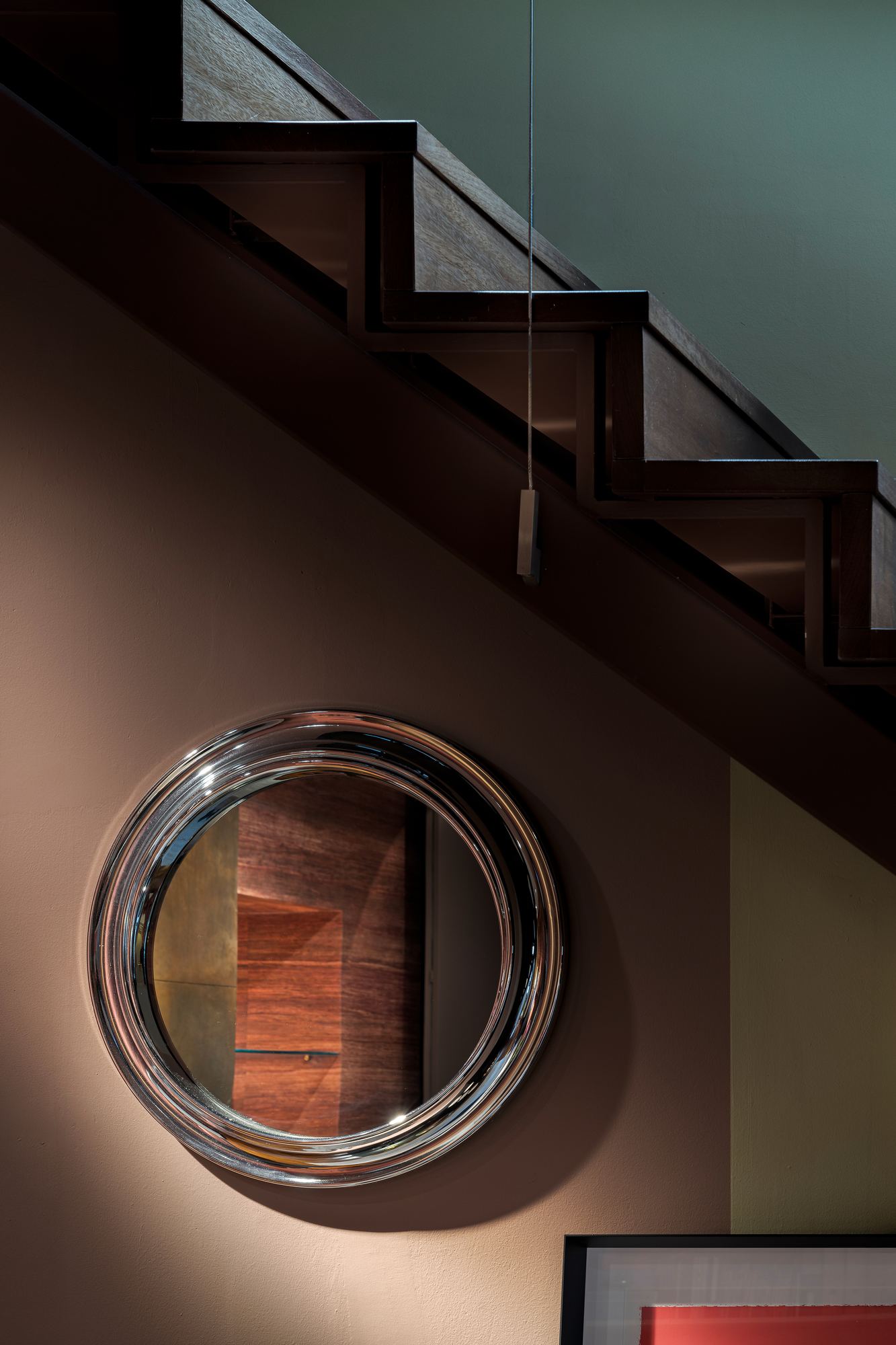 Round porthole window in the wall beneath the stair
