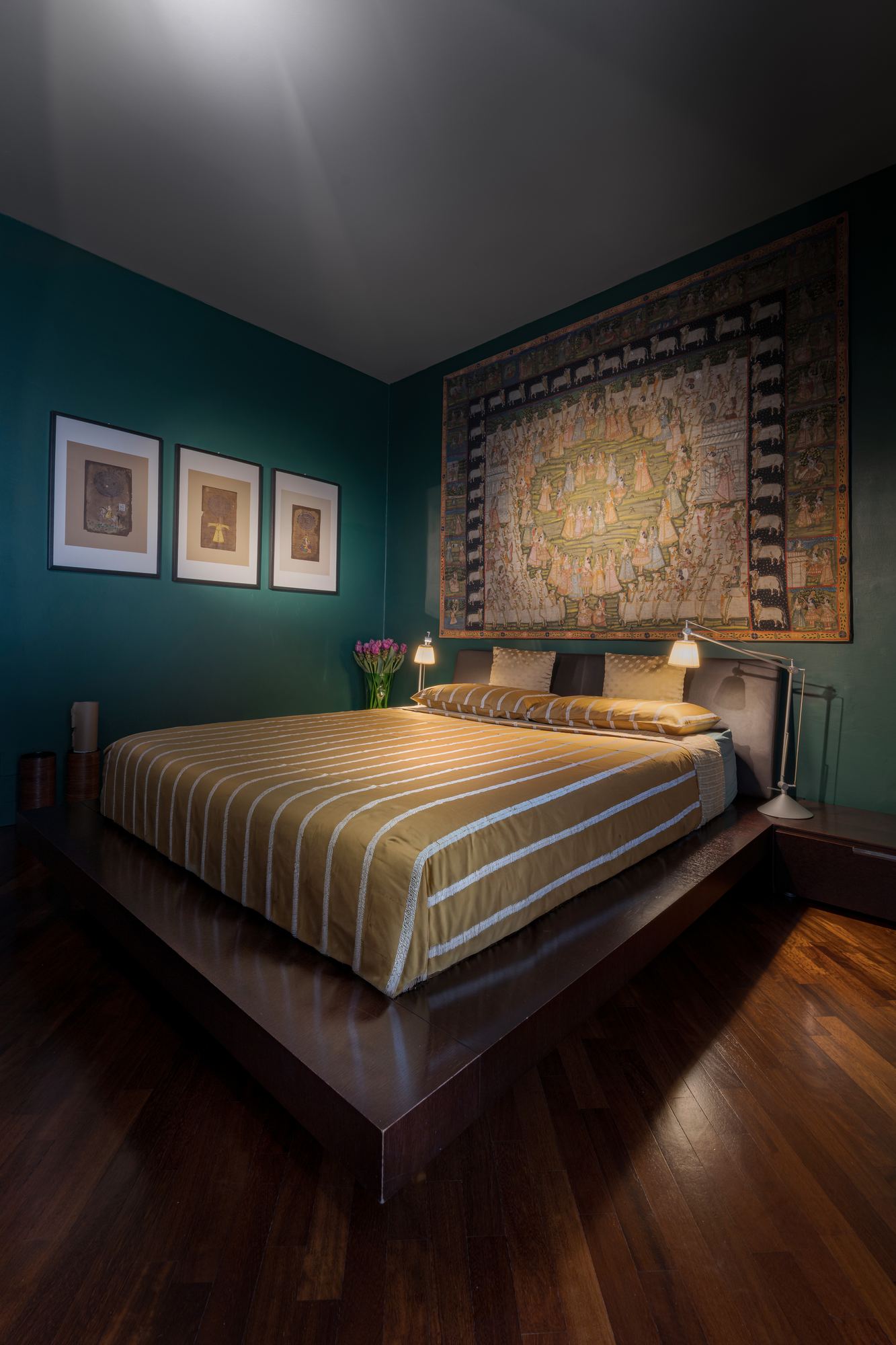 Teal bedroom with a striped bedspread and a large textile above the bed