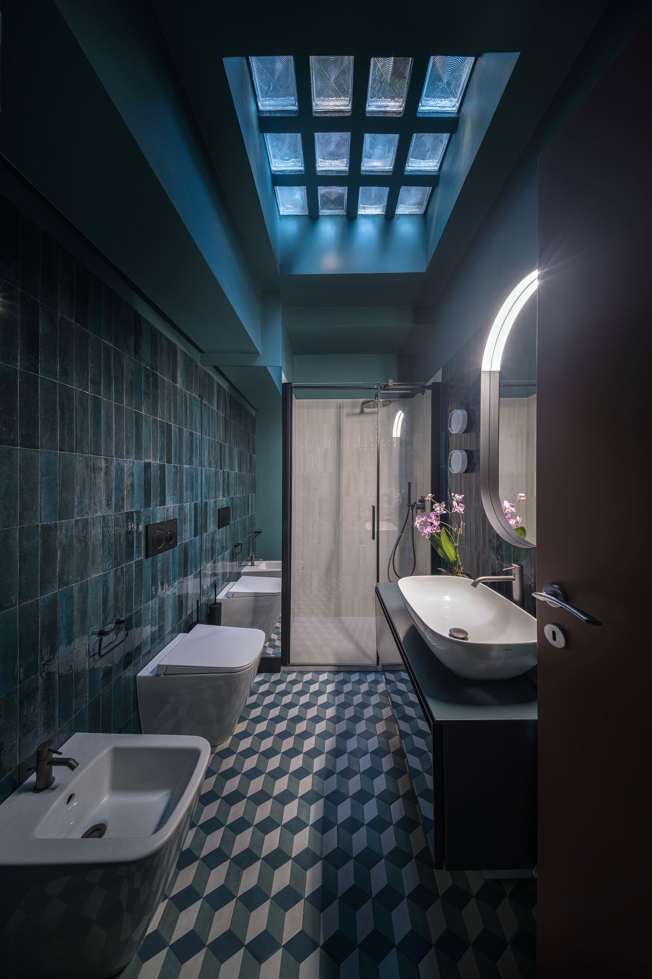 Bathroom with a skylight, blue-green tiles and a geometric floor