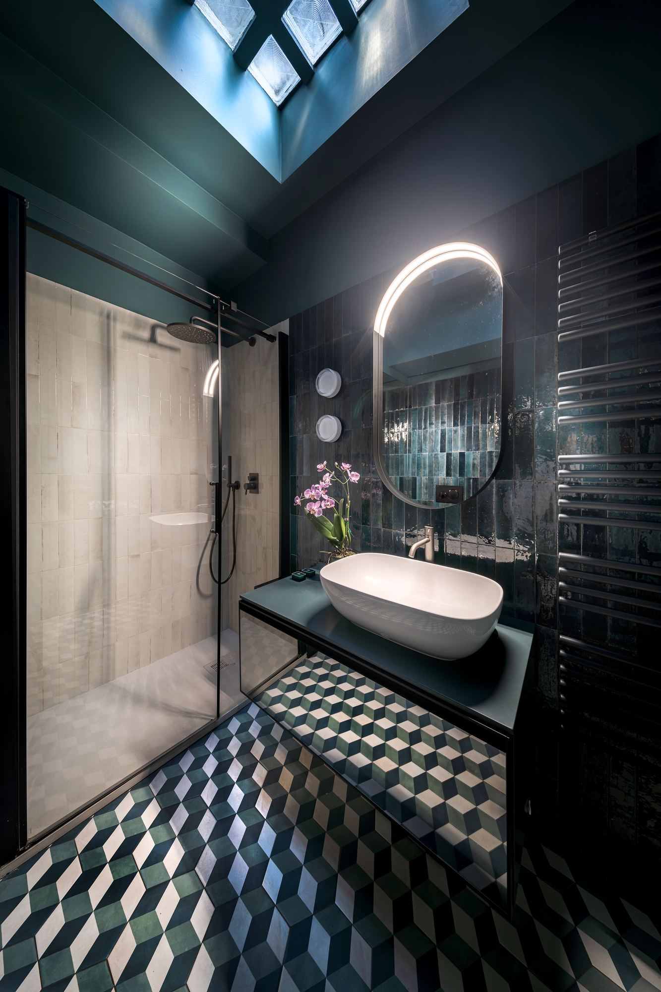 Bathroom with a stone basin, a lit round mirror and a geometric tiled floor