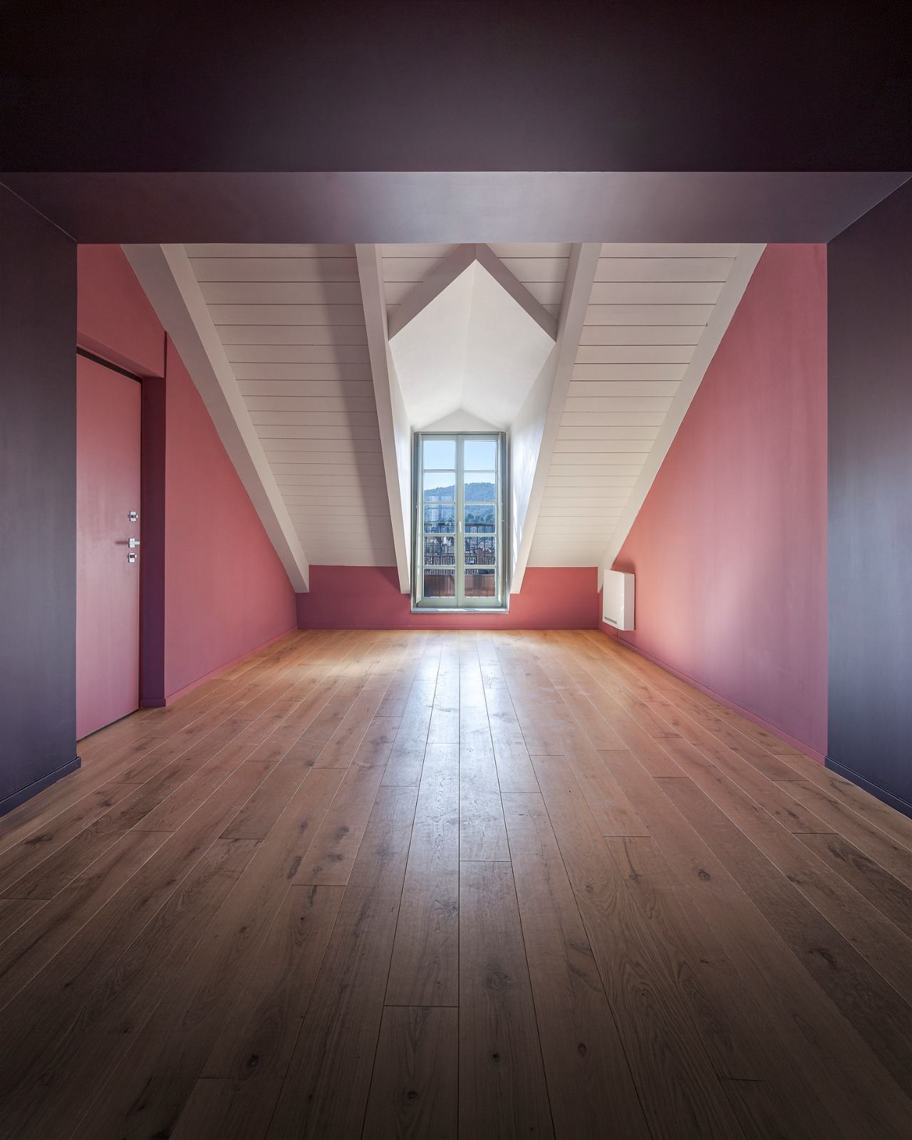 Empty attic with pink walls, a violet beam and a small dormer window