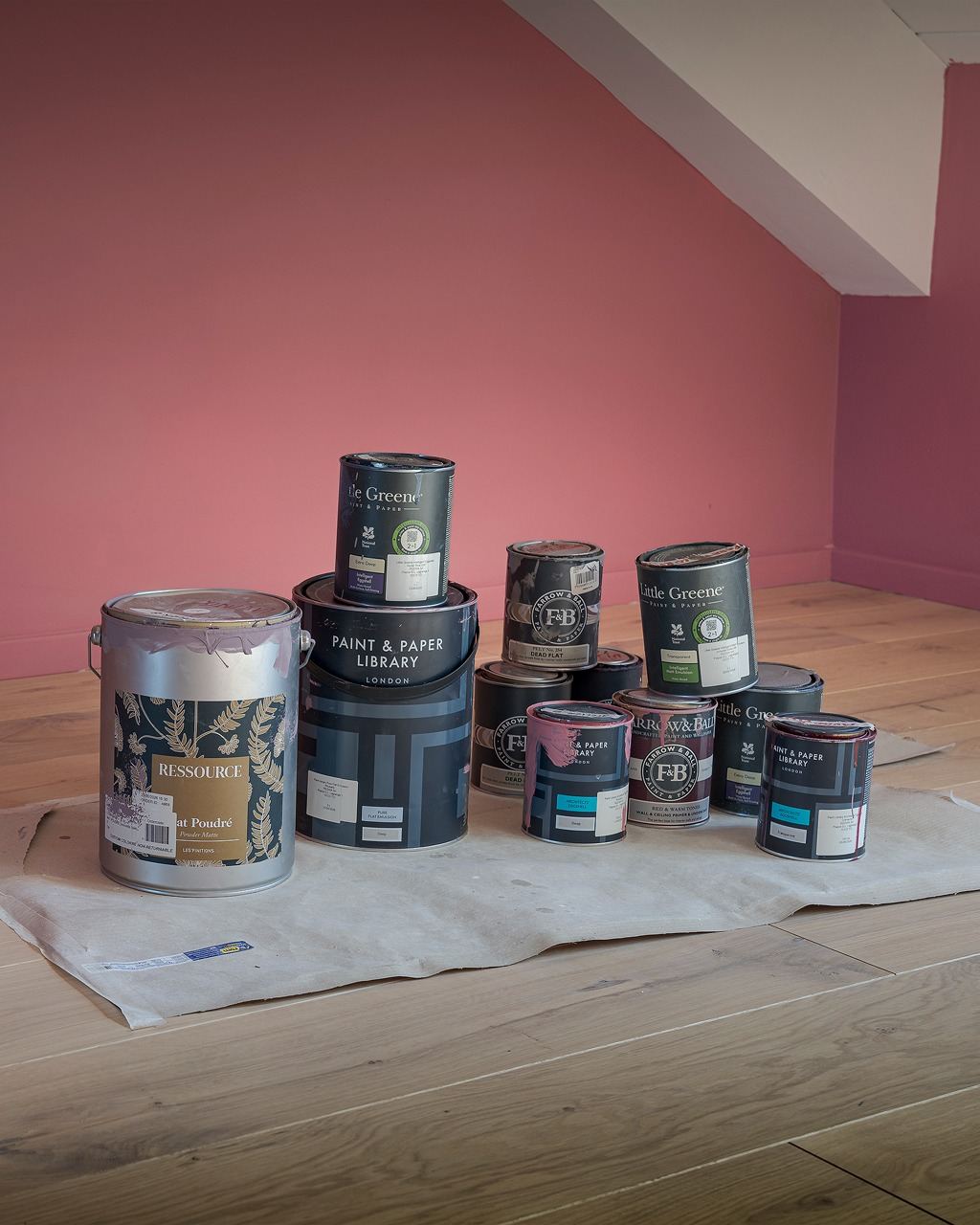 Paint tins stacked on a sheet in a pink room
