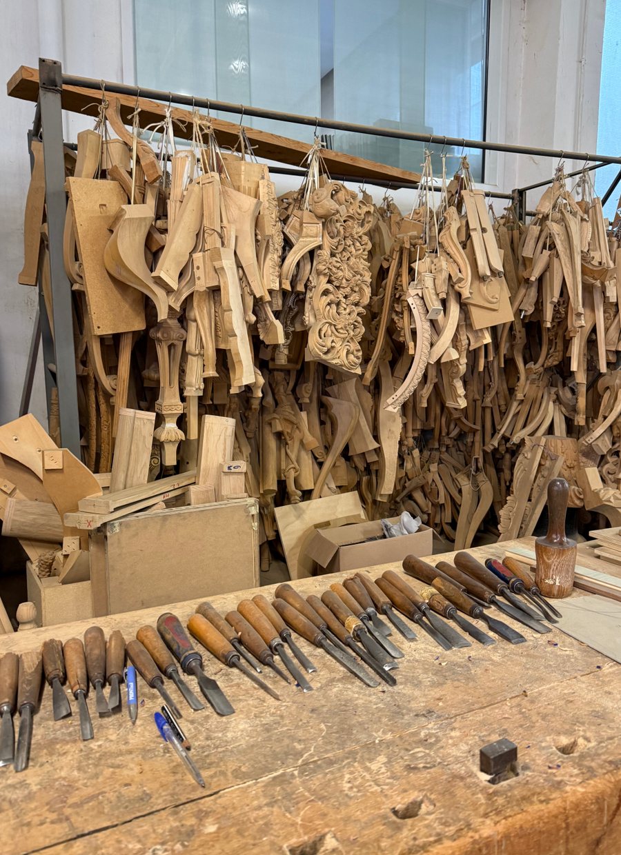 Carved wooden furniture legs hanging above a carver's bench
