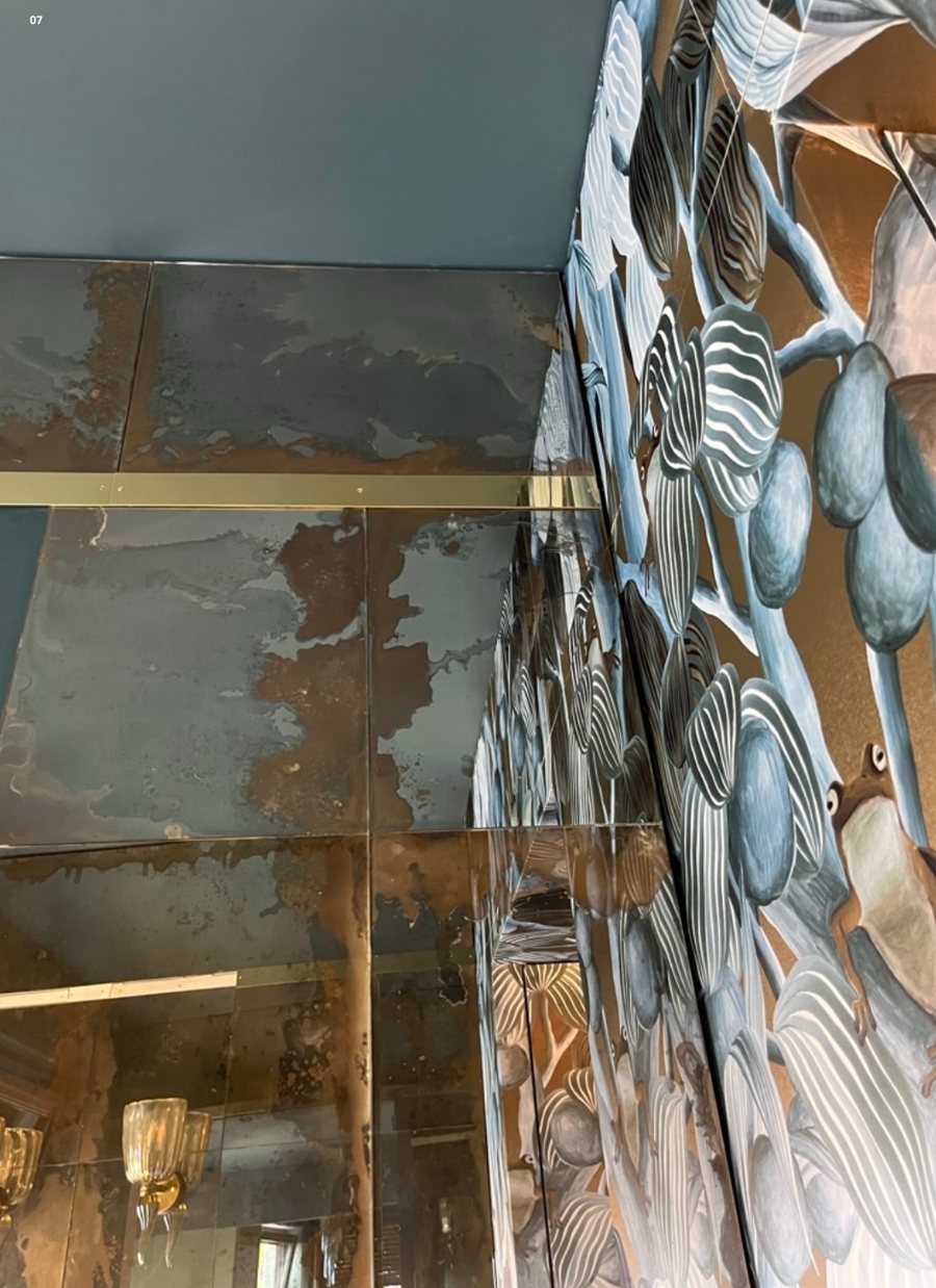 Antique mirror panels beside hand-painted leaf wallpaper